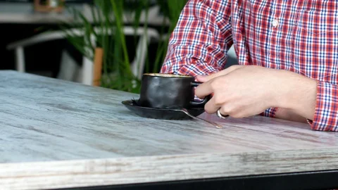 The man is sitting in a cafe with a cup of coffee. Cappuccino. A restaurant Stock Footage 111832810