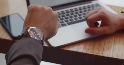 Man sitting in a cafe with a cup of coffee looking at his watch Stock Footage 170088880