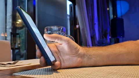 A man is sitting in a cafe with a phone, drinking beer. Stock Footage 240718576