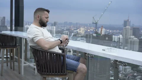 Man sitting in the cafe with the view on the city and using tablet Stock Footage 87544606