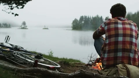 Man Sitting at a Campfire and Warming His Hands Stock Footage 71171772
