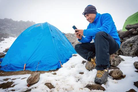 Man sitting in camping tent, using smartphone Stock Photos
