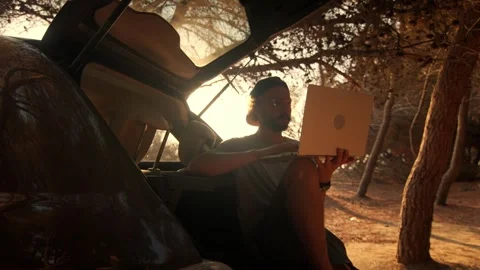 Man Sitting in Car Trunk Working on Laptop, Shot from Inside Vehicle Video stock 341938937