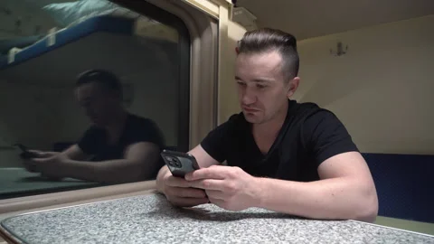 Man is sitting in the carriage of train. He took his phone to take a picture Vídeos de archivo 267956225