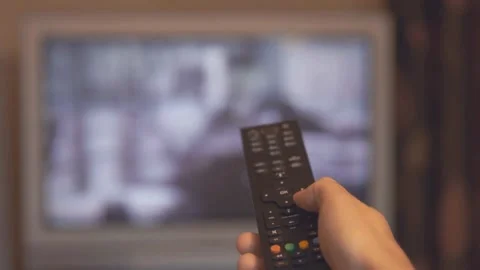 A man sitting in a chair and changes channels TV with remote control at home. Stock Footage 257875235