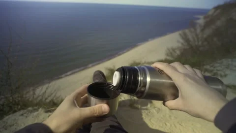 Man sitting in a chair drinking tea on a cliff by the sea. POV shot. Stock Footage 239871972