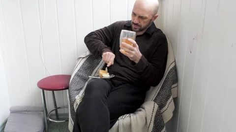A man sitting in a chair drinks a drink and eats cheesecake. Stock-Footage 280474187