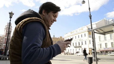 Man sitting in the city and using the phone 動画素材 75393067