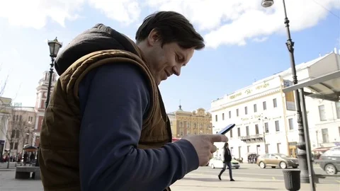 Man sitting in the city and using the phone 動画素材 75393148