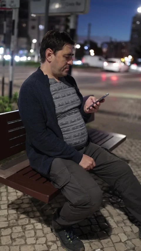 Man sitting on a city bench using smartphone at night Stock Footage 323219223