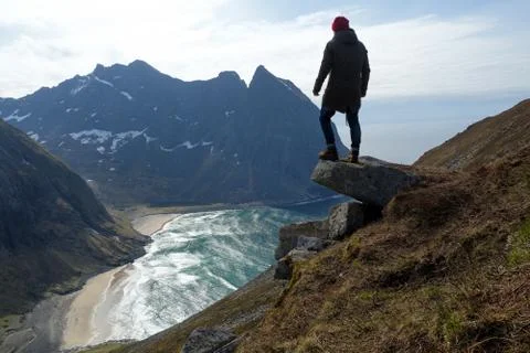 Man sitting on cliff edge alone enjoying aerial view backpacking lifestyle Stock Photos