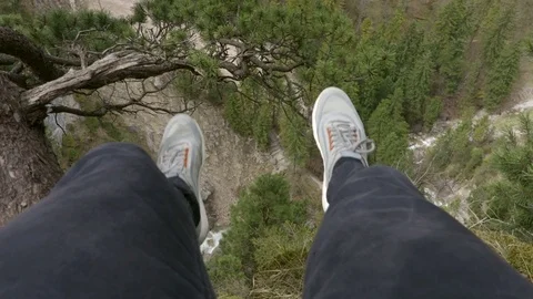 Man is sitting on a cliff in the mountains Stock Footage 75436617
