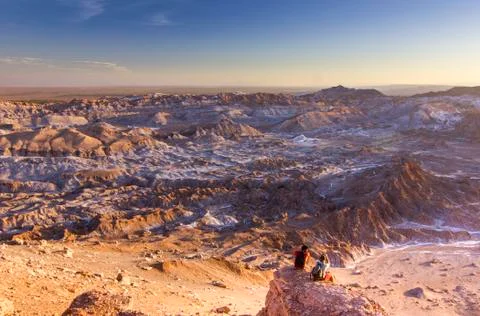 Man sitting on a cliff in salty Moon valley in atacama desert at sunset Stock Photos