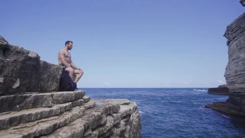 Man sitting on cliffs by the sea. Stock Footage 212495741