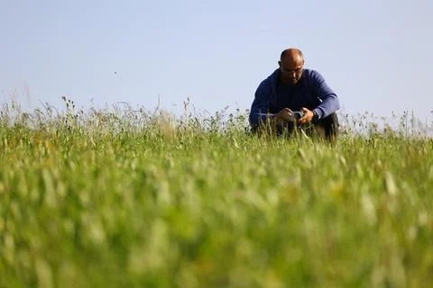 Man Sitting with Compact Camera on Flowering Meadow Edge Stock Photos