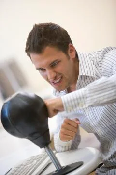 Man sitting in computer room using small punching bag for stress relief Stock Photos