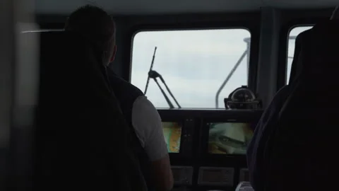 A man sitting at the controls of a small tourist catamaran Stock Footage 233029360