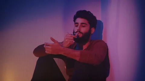 Man sitting in a corner smoking a cigarette Video stock 135388128