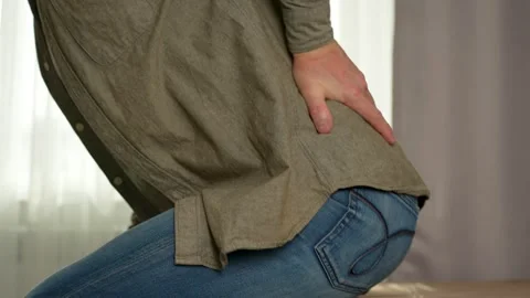 Man sitting on couch and holding his back feels back pain Stock Footage 270730136