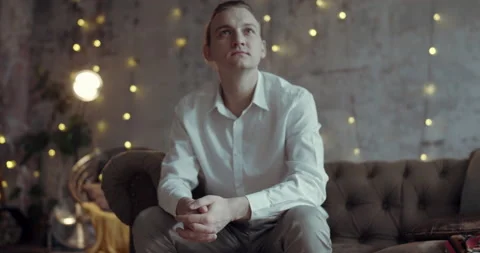 A man is sitting on the couch and looking thoughtfully. Stock Footage 138588469