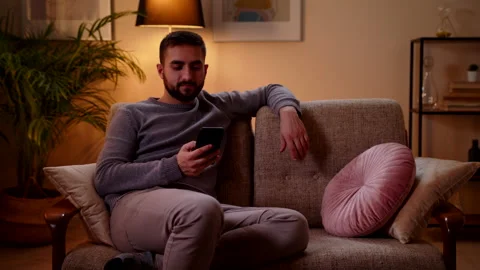 Man Sitting On The Couch And Using Phone Girl Comes With Wireless Controllers Video stock 147000842