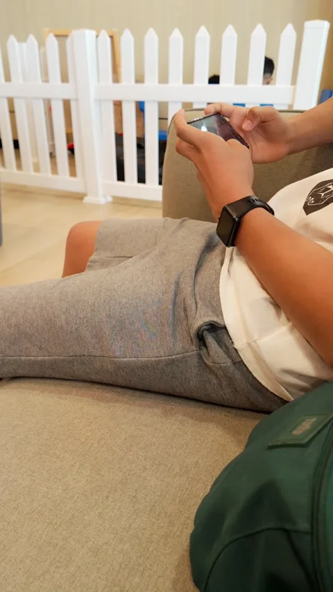A man is sitting on a couch and using his cell phone Stock Footage 328775790