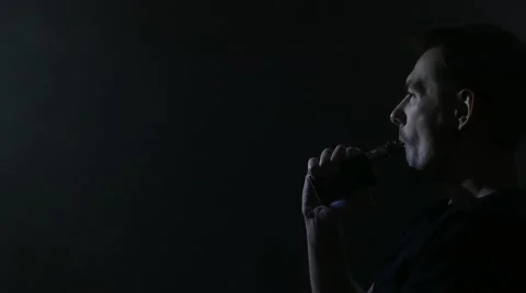 A man sitting on a couch and vaping e-cigarette. 4K UHD Stock Footage 63117204