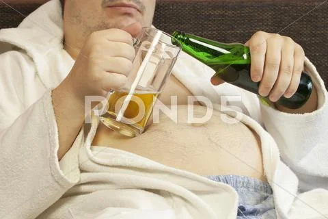 Man sitting on the couch with a beer in the hands of Stock Photos