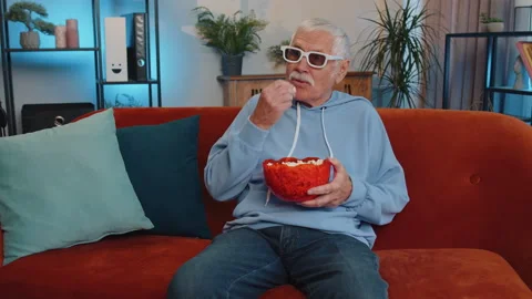 Man sitting on couch eating popcorn and watching interesting TV serial, sport 動画素材 209577415