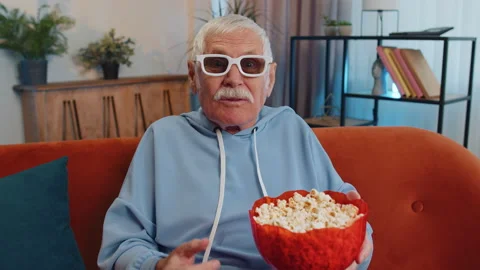 Man sitting on couch eating popcorn and watching interesting TV serial, sport 動画素材 209578592