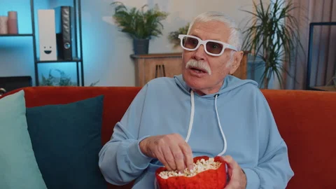 Man sitting on couch eating popcorn and watching interesting TV serial, sport 動画素材 211724117