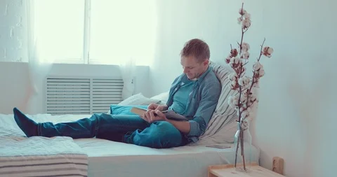 Man sitting on the couch at home reading a book Stock Footage 88387388