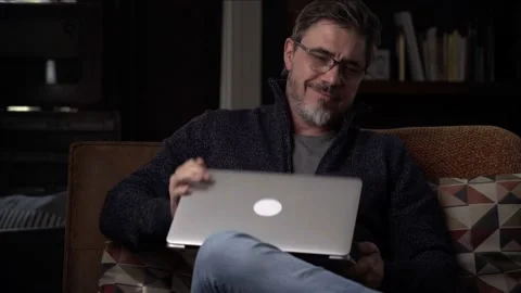 Man sitting on couch at home reading book Stock Footage 150214104