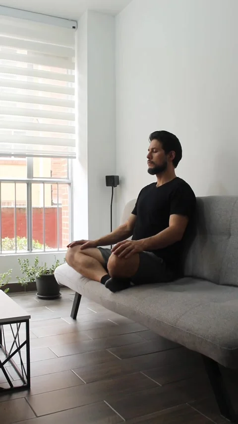 Man sitting on a couch with the legs crossed on a couch in a relaxing attitude Vídeo Stock 340583545