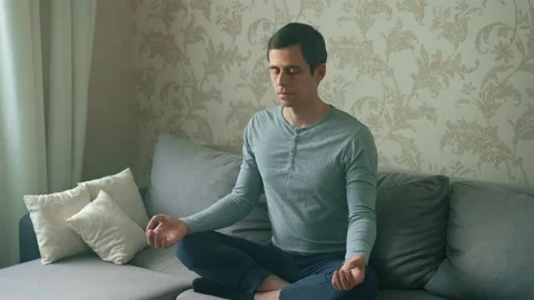A man sitting on the couch meditates Stock Footage 157020130