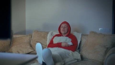 Man sitting on the couch at night with his feet in front of him watching TV Stock Footage 191630257