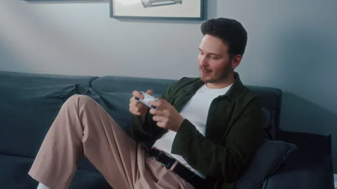 Man sitting on couch playing video game at home Vídeos de archivo 319544149