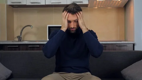 Man is sitting on the couch, praying and takes hands his head Stock Footage 121839091
