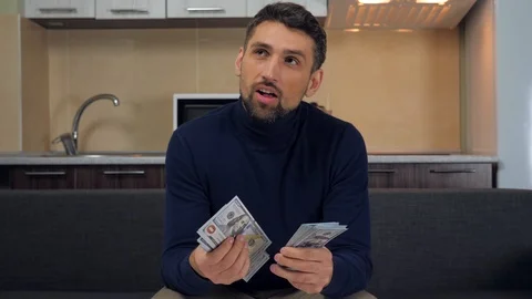 Man sitting on the couch, smiling, counting of money and plans his purchases Stock Footage 121842346