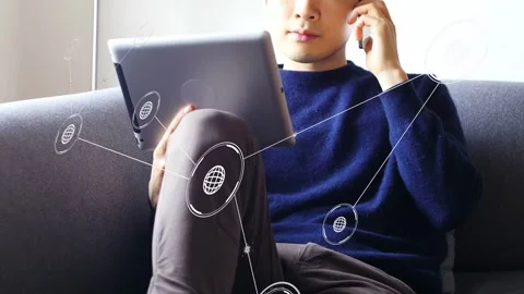 Man sitting on couch tilting tablet, causing network nodes and lines linking Stock Footage 333925457