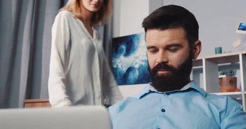 Man sitting on the couch use laptop woman standing smiling feel happy talking Video stock 85571627
