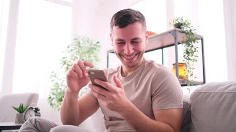 Man sitting on couch using smart phone at home Stock Footage 171544604