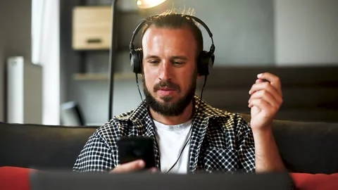 Man sitting on couch using smartphone, smiling young adult male. Stock Footage 136545439