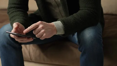Man sitting on couch using smartphone, close-up Stock Footage 263969629