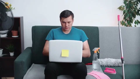 A man is sitting on the couch, working with a laptop. Close-up. Stock Footage 148570309