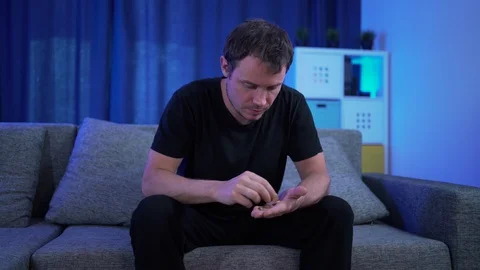 A man sitting counting money on the sofa, very few of them Stock Footage 129300409