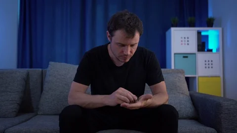 A man sitting counting money on the sofa, very few of them Stock Footage 129300411