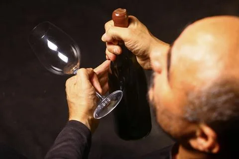 Man sitting in a dark setting with a bottle in hand, Stock Photos