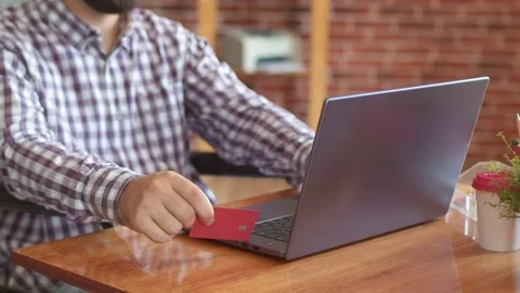 Man is sitting with debit card front of laptop filling out information for Stock Footage 158176782