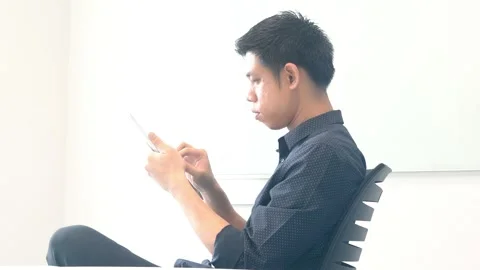 A man is sitting at a desk and looking at a tablet Stock Footage 314899391